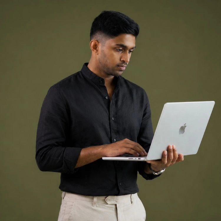A man in a black shirt holding and using a silver laptop